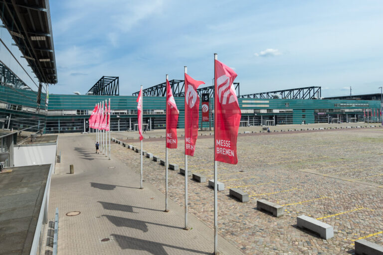 Rote Fahnen der Messe Bremen wehen vor den Messehallen